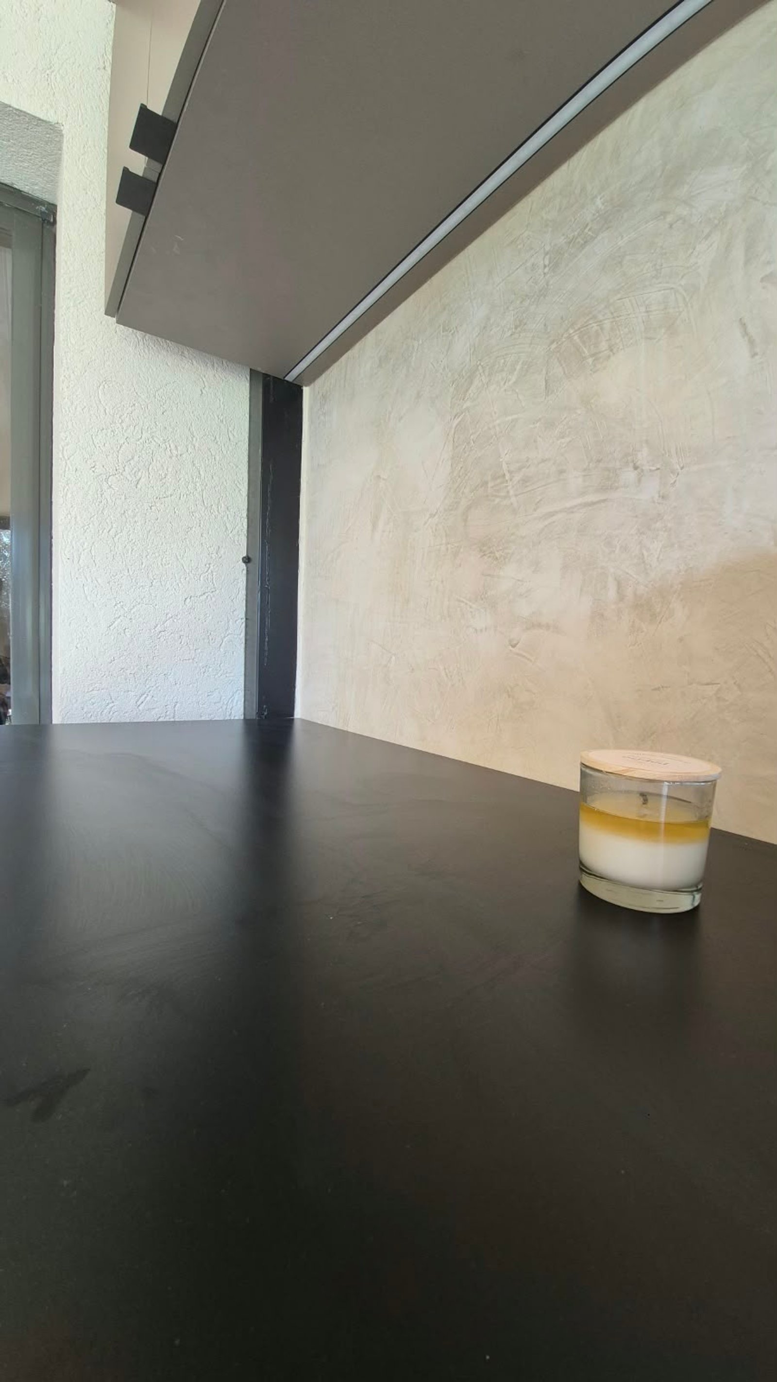 Interior moderno con suelo negro y pared texturizada de microcemento — proyecto OBRA JJ, por Cc Arquitectura & Diseño, en Colectora Au RN 20 km14